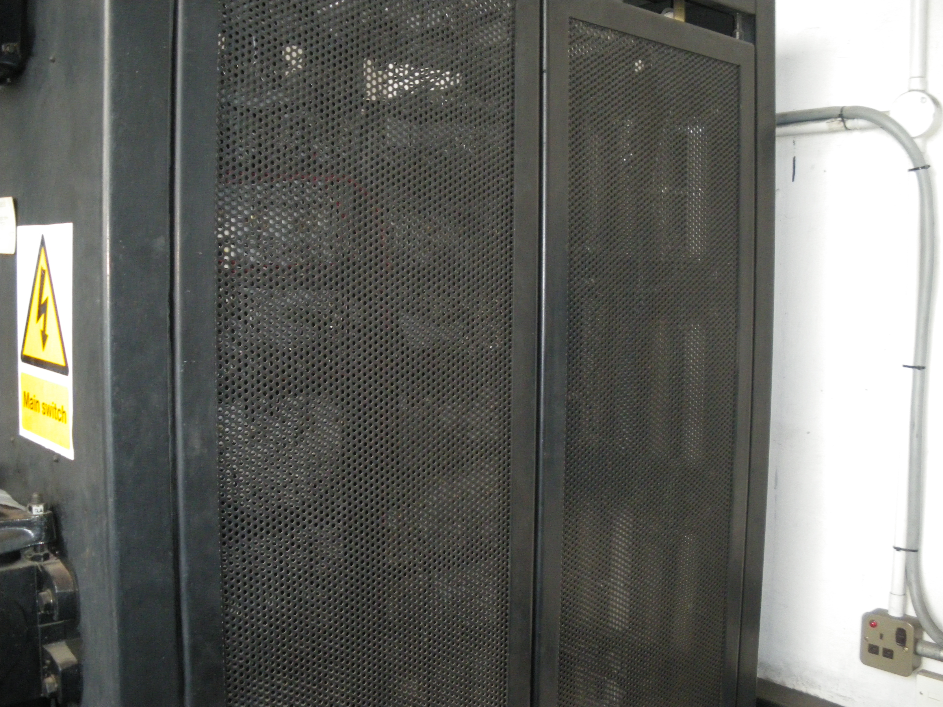 E lift, rear of control cabinet.